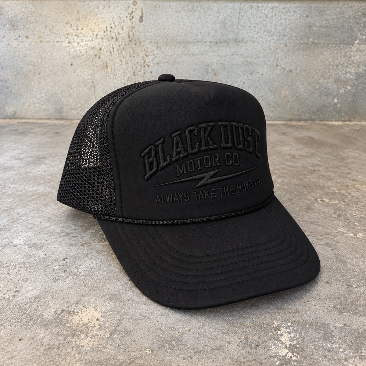 Black foam trucker hat with embroidered Black Dust Motor Co. logo, three-quarter view